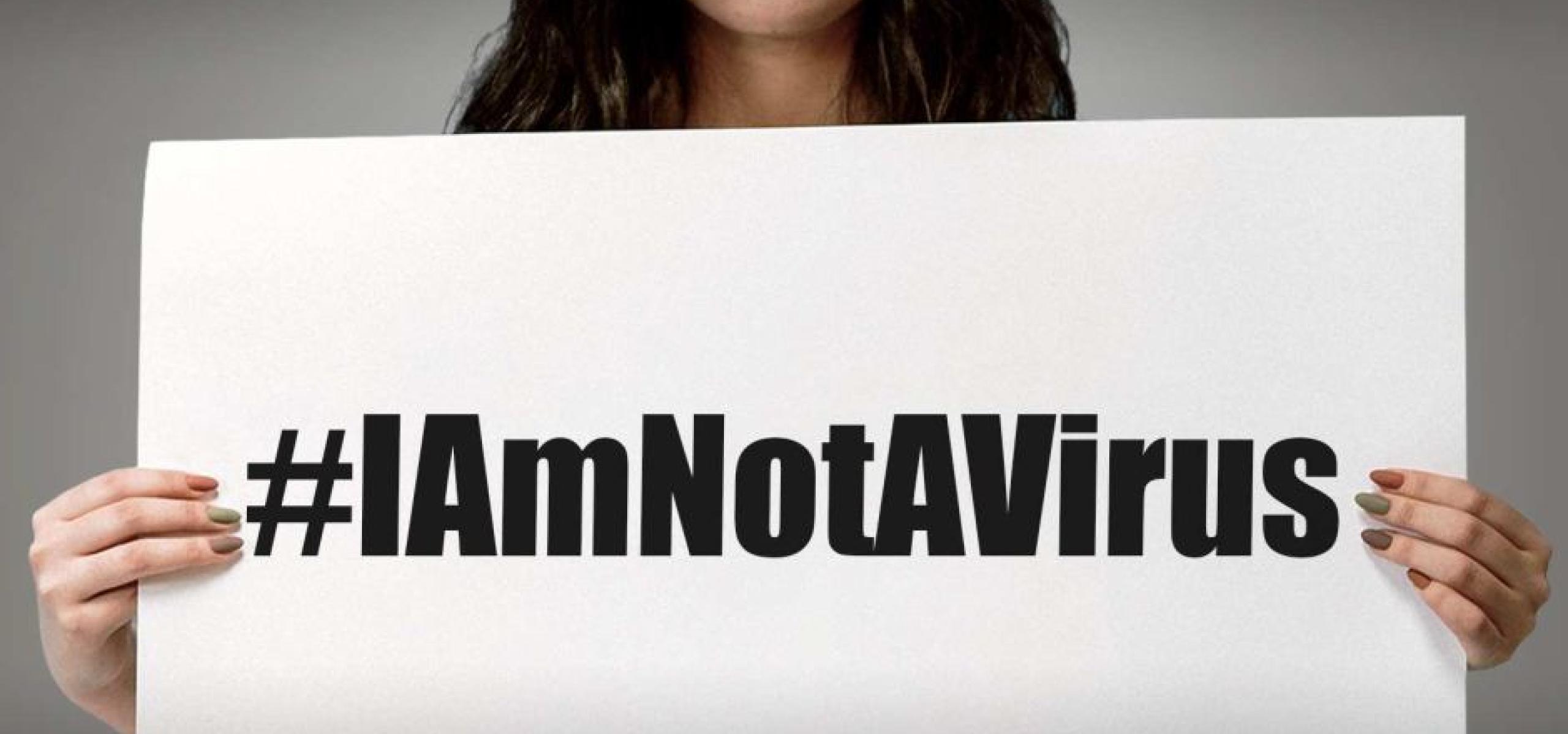 Person holding #I am not a virus paper