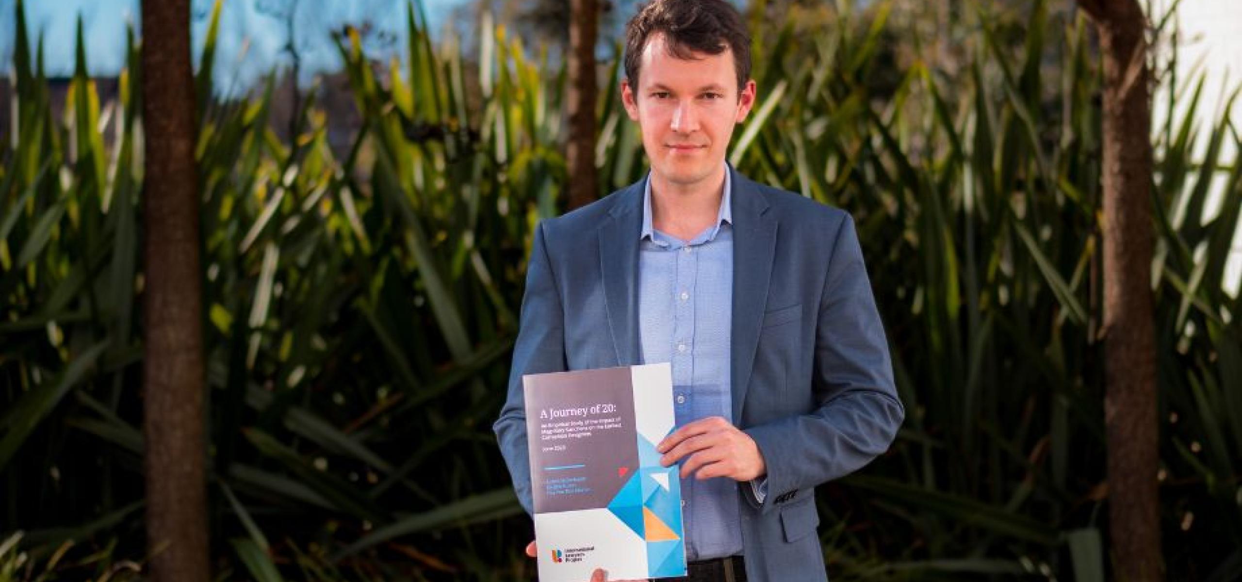 Dr Anton Moiseienko holds a copy of his report, 'A Journey of 20: An Empirical Study of the Impact of Magnitsky Corruption Sanctions'